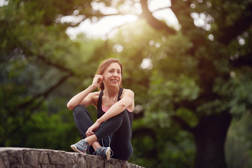 Naklejka premium Cheerful sportswoman with headphones in park