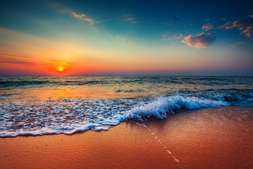 Beautiful sunrise over the sea and breaking ocean wave