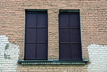 Fototapeta na wymiar два старых окна закрытые коричневый железом на кирпичной стене