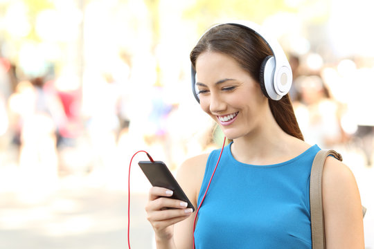 Girl listening to music wearing headphones on the street