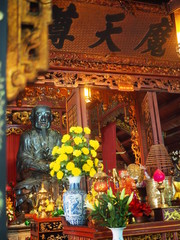Old man statue in Chinese shrine, with respecting yellow marigold flower