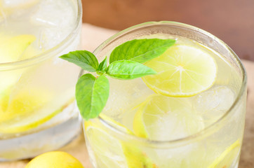 Cold lemonade with ice and fresh slice lemon in the glass on wooden plate,Healthy drink in summer