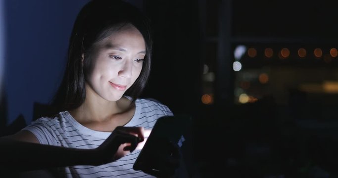 Housewife looking at mobile phone at night