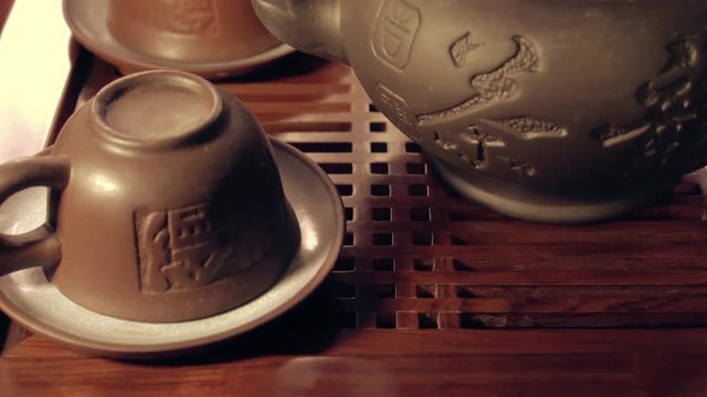 Tilt shot of clay cups and tea pot on chaban. Traditional chinese tea ceremony on the tea table.