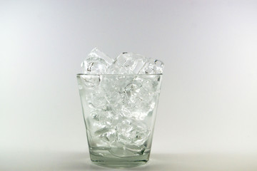 Ice cube in the glass over the white background, soft focus