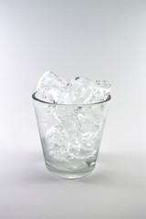 Ice cube in the glass over the white background, soft focus