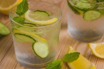 Detox water, fresh organic lemonade with ice, cucumber, lemon and mint on wooden background