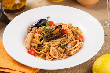Pasta with seafood and tomatoes. Served in a plate on the table.