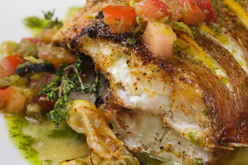 Fried fish with vegetables and lemon sauce. Close up.