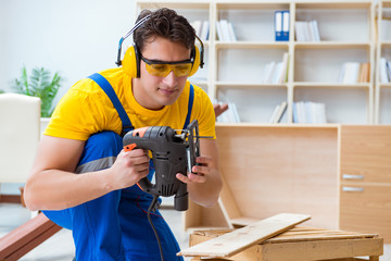 Repairman carpenter cutting sawing a wooden board with an electr