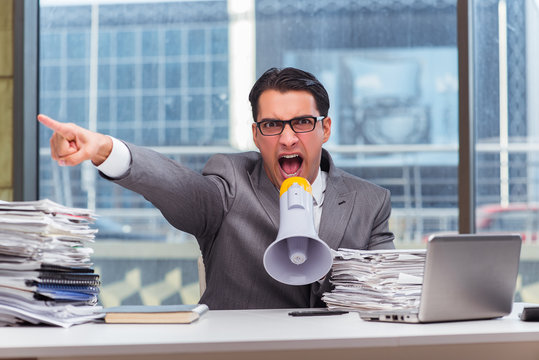 Angry businessman with loudspeaker in the office