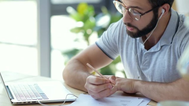 Pensive man with earphones attending online courses