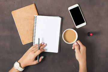 Flat lay women workspace female hands, coffee, notebook, smartphone, lipstick