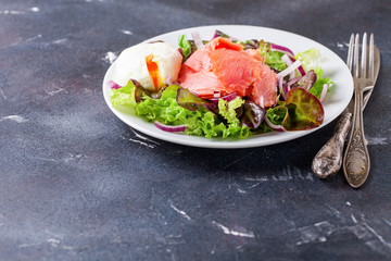 Healthy food - vegetables and salmon salad on a dark background. Selective focus. Copy space