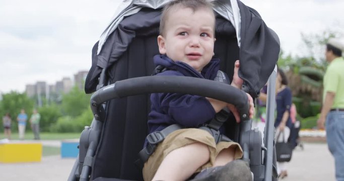 Toddler boy in stroller looking frantically for parents