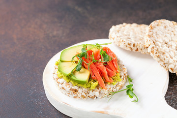 Sandwich crispbread with avocado and a salmon against a dark background. Selective focus. Copy space