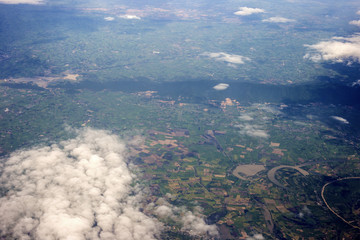 aerial photo from window of plane, above ground and cloud, green field under the clouds
