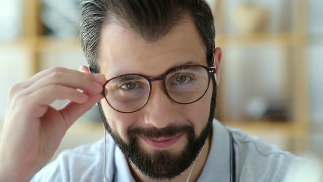Positive student taking off glasses while smiling into camera