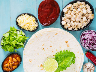 Traditional mexican tortilla with mix of ingredients on blue wooden background