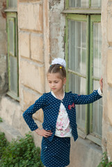 cute little girl in a fashionable costume is standing by the house