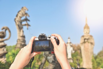 Tourist Holding a Vintage Mirrorless Camera While Taking a Photograph
