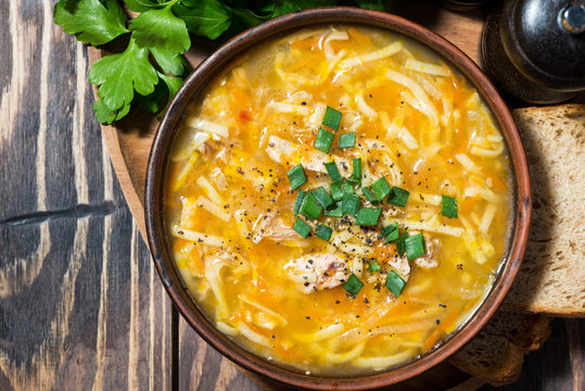 chicken soup with egg noodles on wooden background, top view closeup