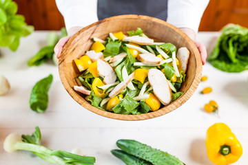 hands holding an healthy checken salad in a bowl