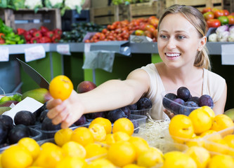 Woman looking plums in fruit store