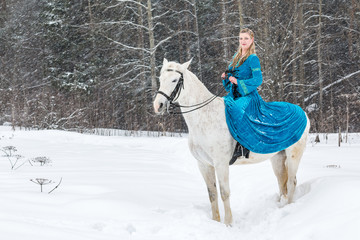 Woman in national dress and white horse in a winter forest