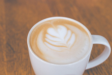 cup of hot latte art coffee on wooden table