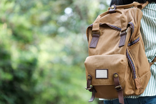 Backpack traveler closeup over green tree nature background with copy space for text, travel and lifestyle concept