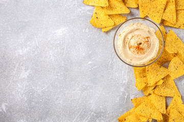 Hummus and nachos on a gray background.