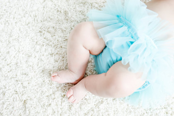 Close-up of legs and feet of baby girl on white background wearing turquoise tutu skirt. © Irina Schmidt