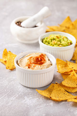 Hummus and guacamole with nachos on a gray background. Selective focus. Copy space