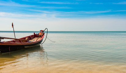 Fototapeta na wymiar wooden fising boat on blue sky and sea beach wiht copy space.
