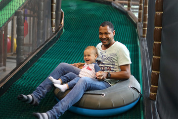 Father and son sliding at a indoor playgrounds