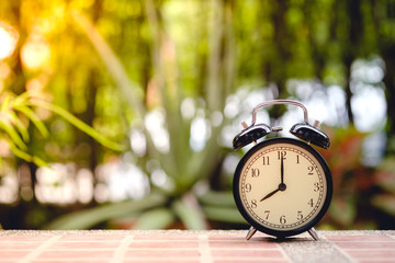 black vintage alarm clock or retro alarm clock with blurred garden view background