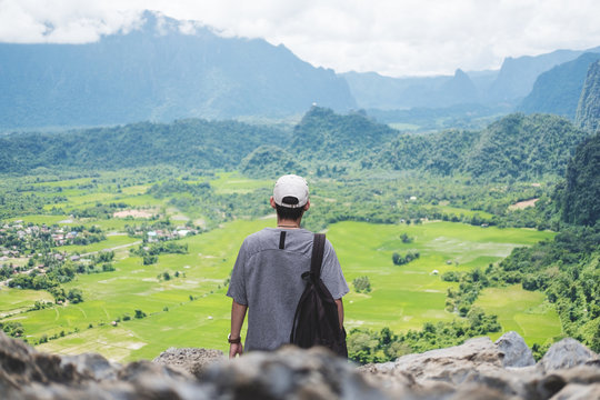 Young man with backpack enjoying beautiful landscaped nature view on top of the mountain in Laos, Traveling leisure activity hiking to sightseeing spot