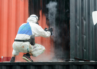 man painting with graffiti aerosol can, outdoors. Process of painting
