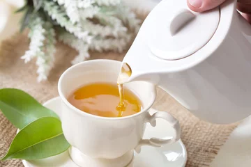 Photo sur Plexiglas Theé Close up pouring hot black tea in a white tea cup ,  Tea ceremony time concept