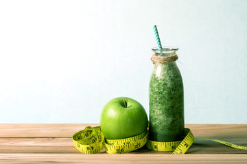the Healthy fresh  green smoothie juice in the glass bottle on wooden table with the green apple and green apple for healthy detox and diet  habits concept