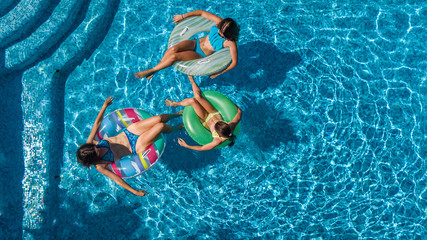 Aerial top view of family in swimming pool from above, mother and kids swim and have fun in water on family vacation in hotel resort
