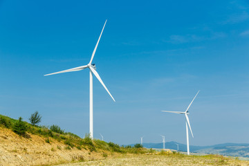 Wind turbines standing on a heels among fields