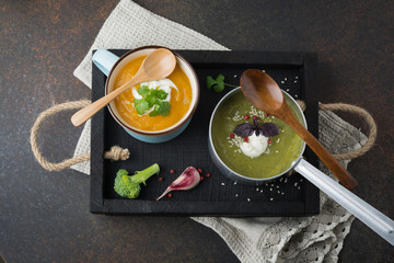 variety of vegetarian soups  cream of carrot and broccoli cabbage on a dark concrete background....