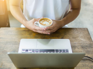 laptop and heart coffee cup in business man hands