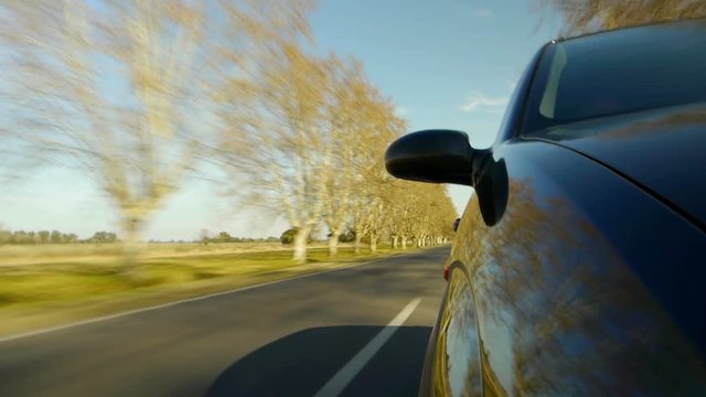 Driving a car, windshield reflection. Hood side reference. Mounted camera, front view. Black car ride. Country road, trees on the side, blue sky, day. Real Time Speed. HD. Right side wheel driving UK