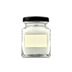 Salt in a glass bottle isolated on white background. Empty yellow stick note paper and black lid. Modern and stylish. Close up.
