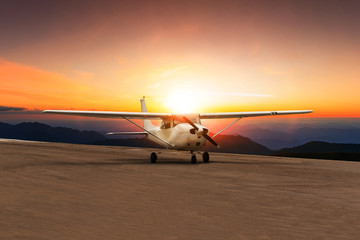 old propeller plane taxi on airport runway against beautiful sun set sky