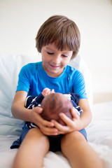 Cute boy, brother, meeting for the first time his new baby brother at hospital