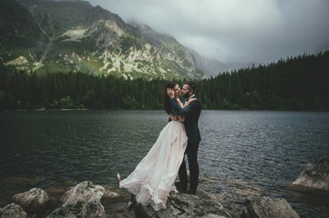 bride with the beautiful blue dress and groom with views of the beautiful green mountains and lake with blue water